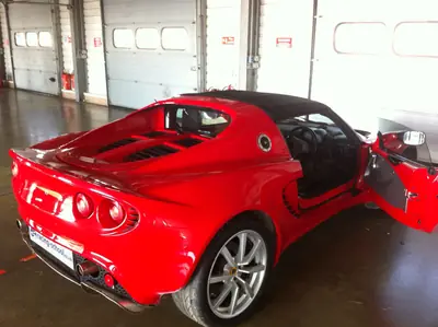 Red Lotus Elise with door open in the pit garage