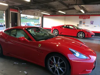 Two Ferraris, a California and an F430, parked together in the pit garage