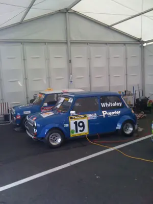 Blue racing Minis parked in the pit garage under cover