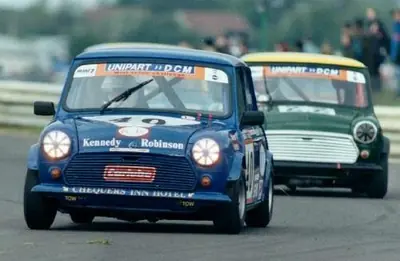 Historic photo of a blue racing Mini competing wheel-to-wheel on circuit