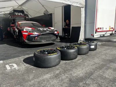 SWR Performance Aston Martin Vantage GT4 race car in the pit garage with a fresh set of tyres stacked in front